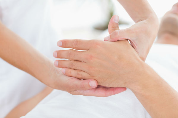 Behandler som presser på et område av hånden til en pasient
