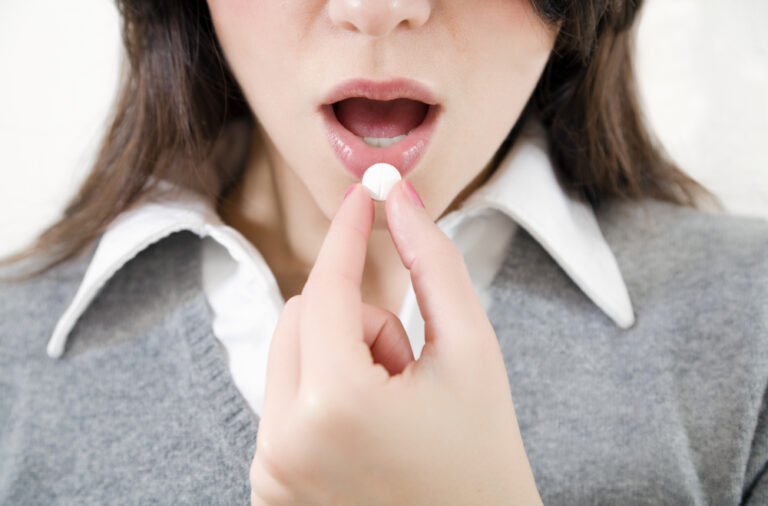 Kvinne holder pille foran munnen